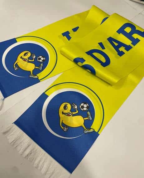 Écharpe jaune et bleue avec mascotte souriante jouant au foot et texte D'AR, accessoire de supporter dynamique.