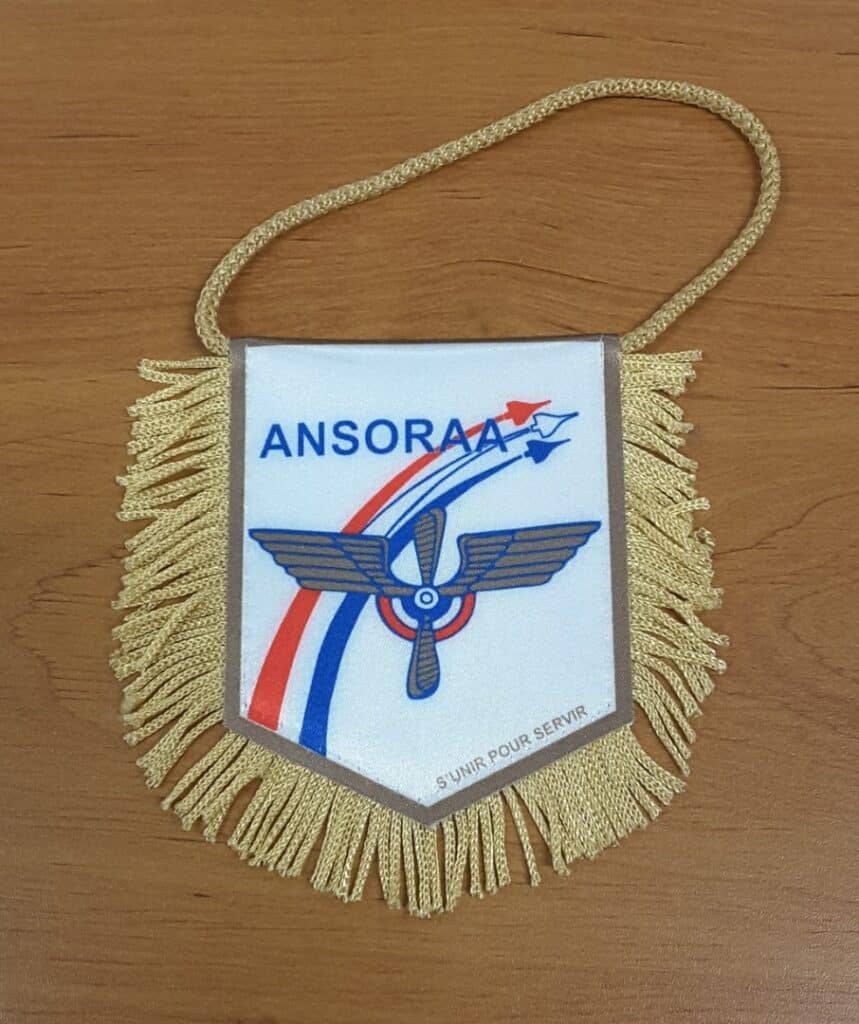 Fanion blanc ANSORAA à franges dorées avec logo ailé, avions tricolores et devise S'unir pour servir.