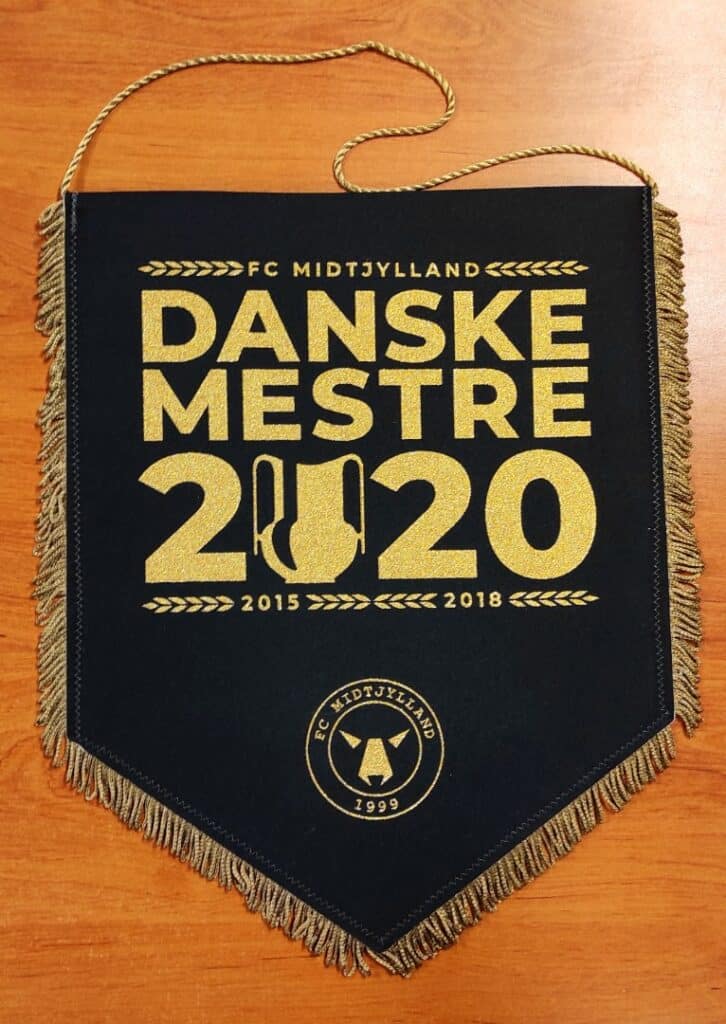 Fanion noir et or FC Midtjylland célébrant le titre Danske Mestre 2020, avec dates 2015-2018 et logo du club.