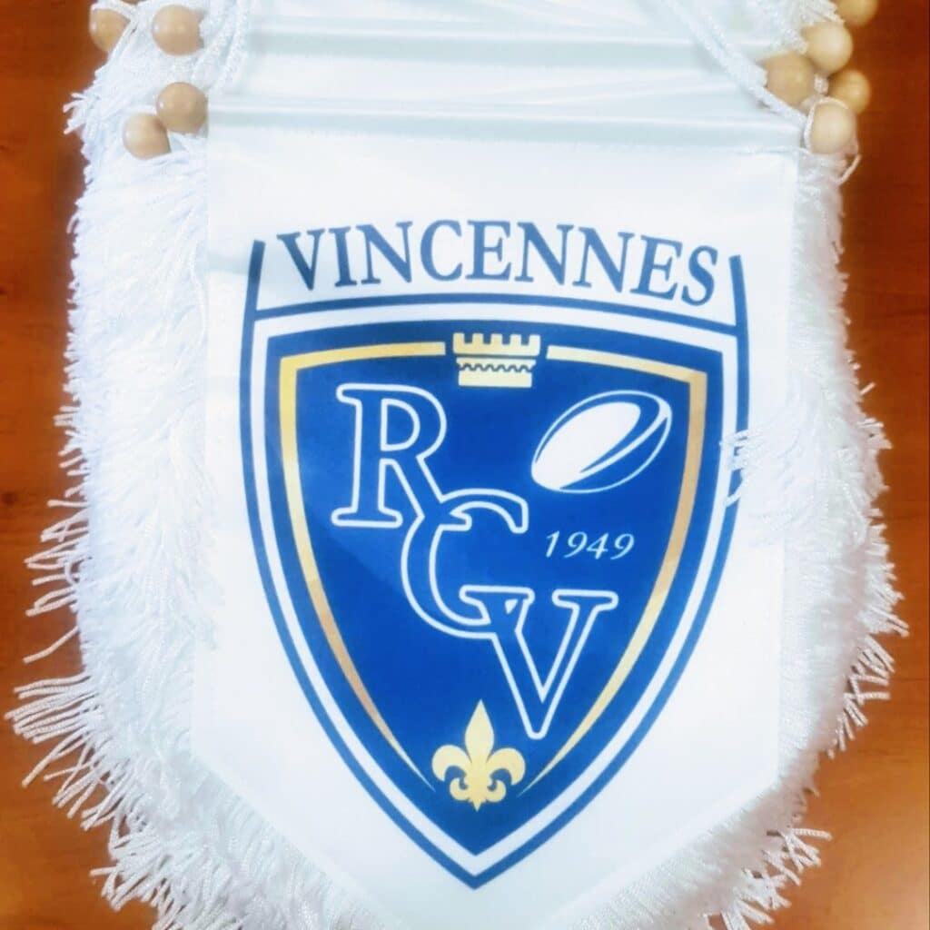 Fanion du Rugby Club Vincennes (RCV) avec blason bleu, ballon de rugby, fleur de lys et date de fondation 1949.