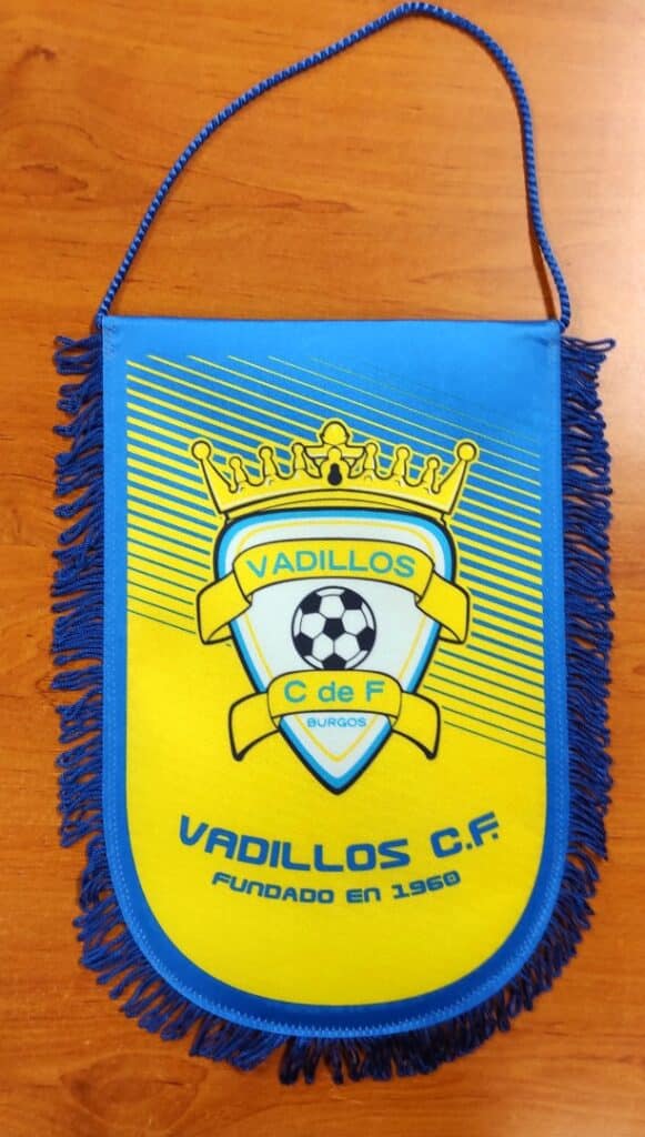 Fanion bleu et jaune du club de foot Vadillos C.F. Burgos, fondé en 1960 avec logo de ballon et couronne.