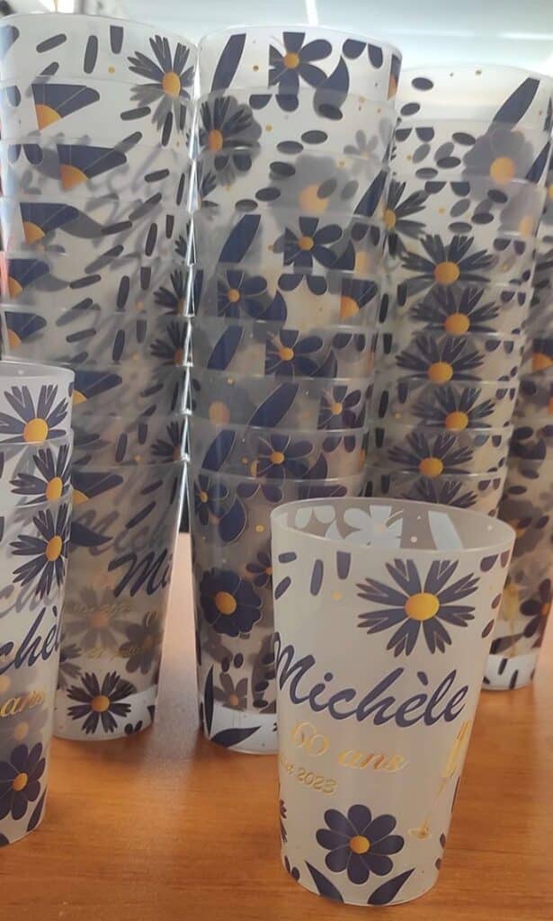 Gobelets personnalisés Michèle 60 ans à motif floral bleu et jaune pour un anniversaire en juillet 2023.