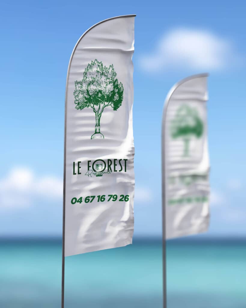 Drapeau publicitaire Le Forest Restaurant en bord de mer Oriflamme Le Forest Restaurant avec logo arbre vert et numéro 04 67 16 79 26 sur une plage ensoleillée.