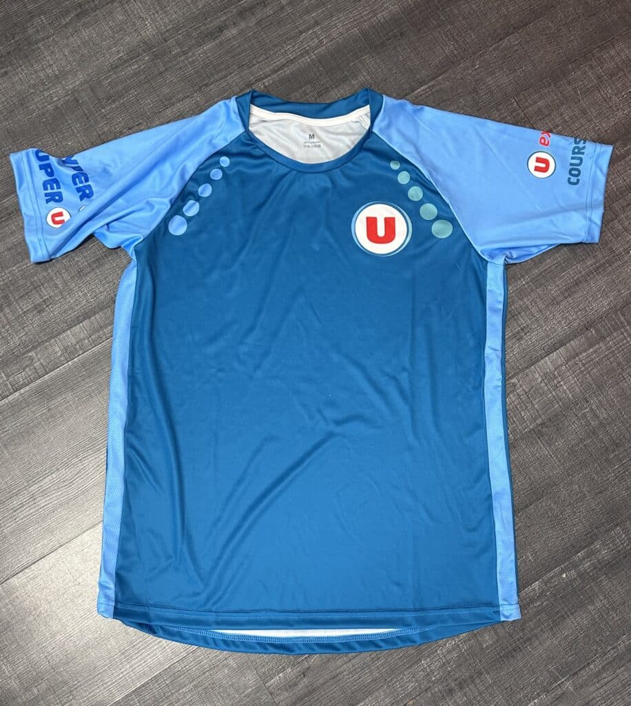 Maillot de sport bleu bicolore avec logos Super U, Hyper U et Courses U. Design à pois sur les épaules, taille M.
